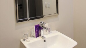Une salle de bain avec un lavabo blanc, un miroir et un robinet.