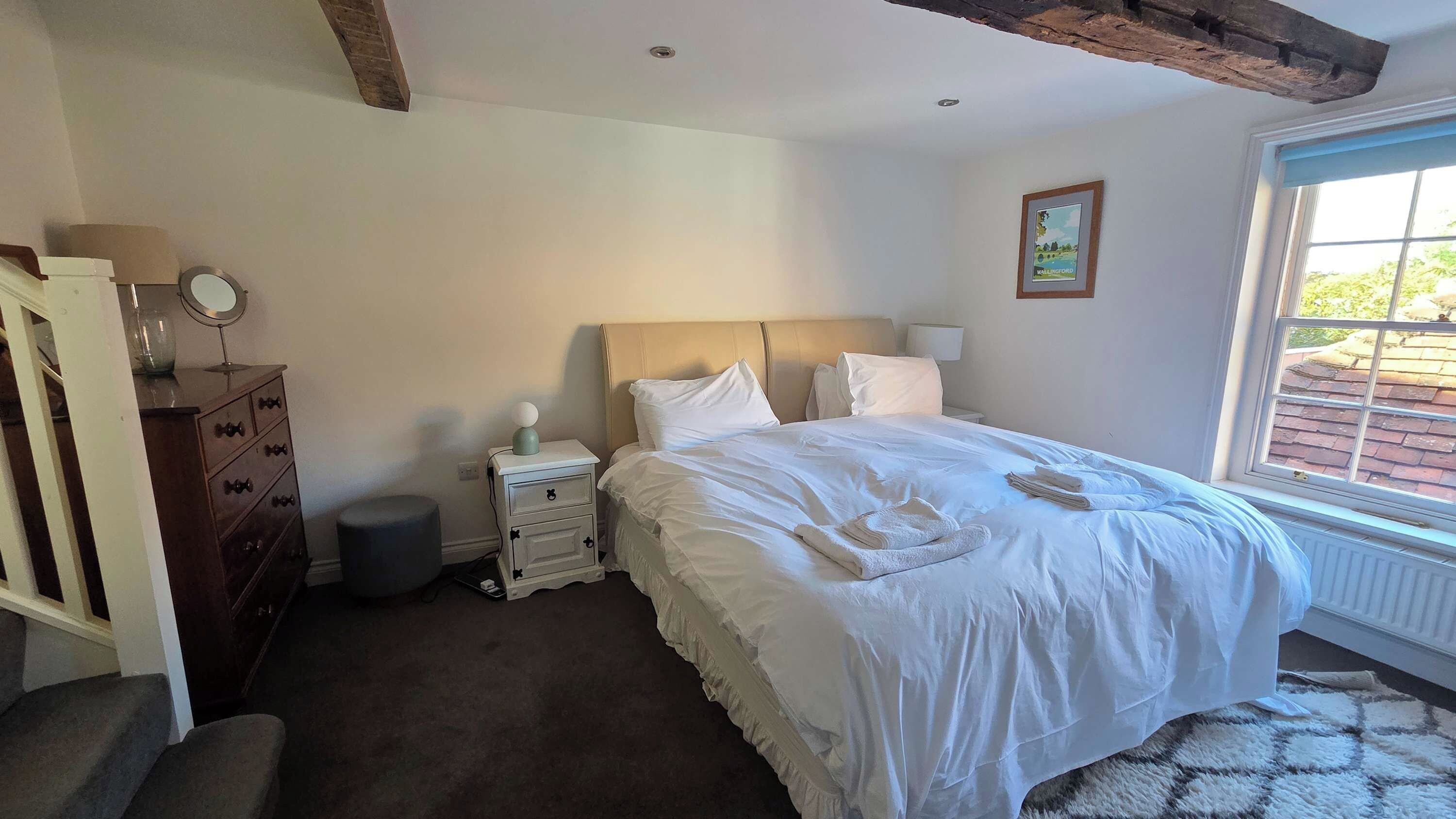 A bedroom with a bed, a nightstand, a dresser, and a window with a view.