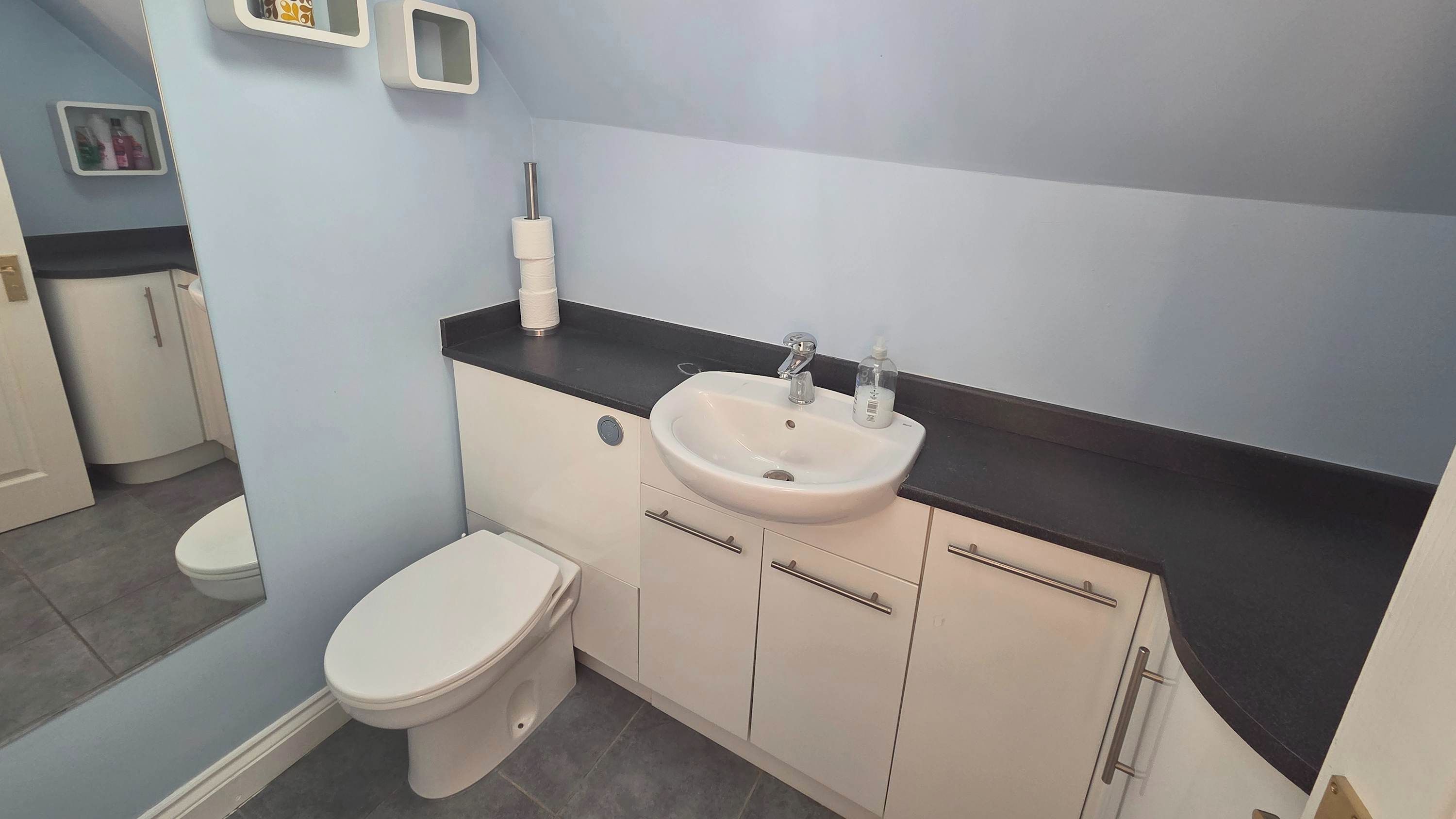 Een badkamer met een toilet, een wastafel en kastjes.