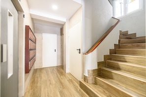 Ein Flur mit Holzboden, einer Holztreppe und einer Tür am Ende.