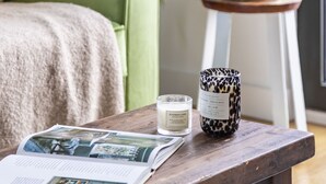 A wooden table with a magazine, a candle, and a decorative item. - Modern 1BR Kings Cross Hideaway (London)
