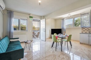 Une chambre d’hôtel moderne équipée d’un canapé, d’une table à manger, de chaises, d’un téléviseur et d’un coin cuisine.