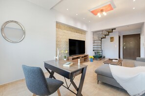 Una sala de estar moderna con un televisor de pantalla plana, una mesa de comedor y una escalera que lleva a otro nivel.