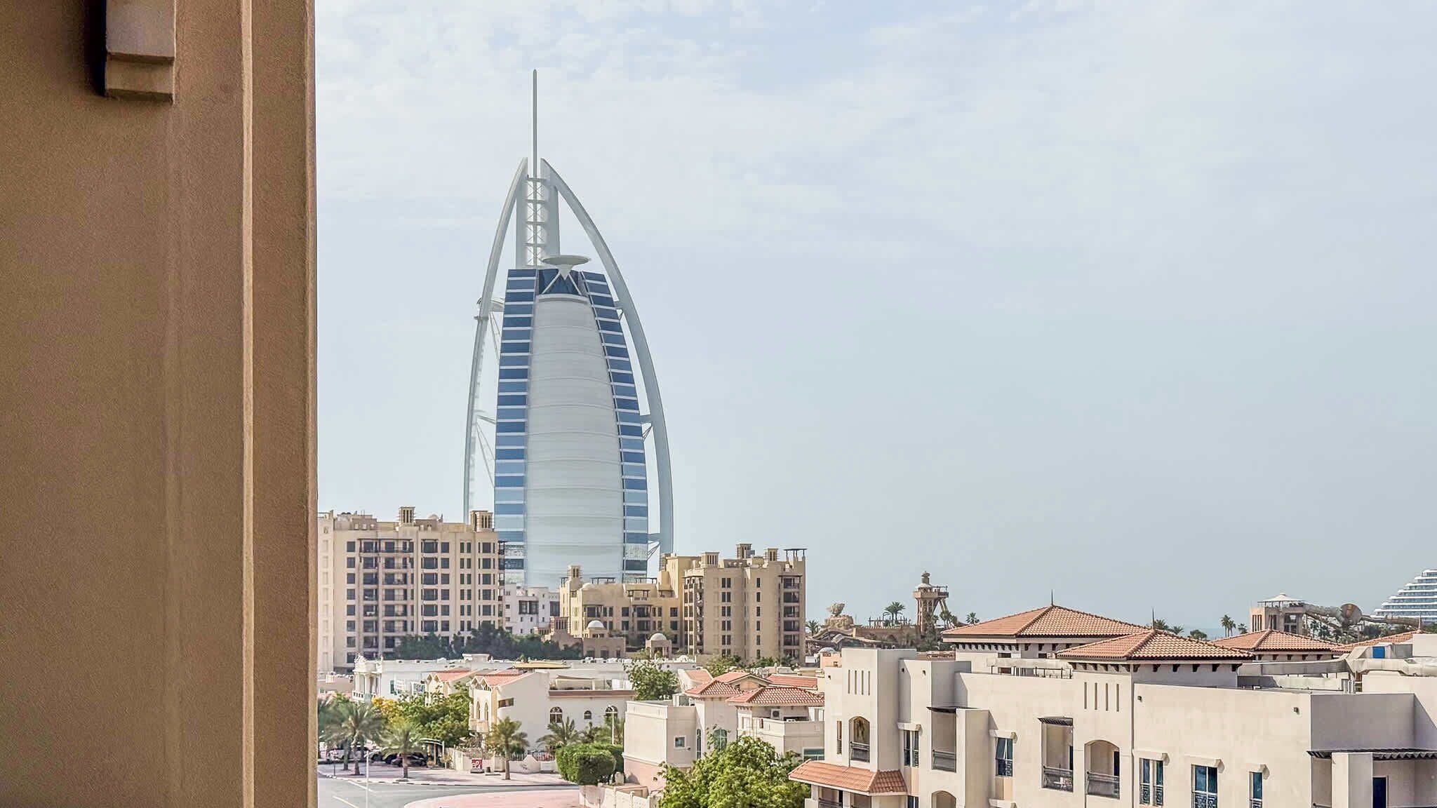 A view of a cityscape with a prominent modern skyscraper, a variety of residential buildings, and a clear sky.