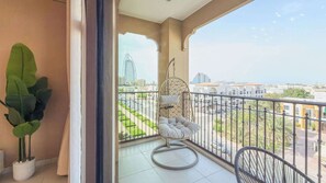 Ein Balkon mit Hängesessel, Blumentopf und Blick auf eine Stadtlandschaft mit Gebäuden und einer Brücke.