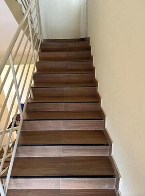 Eine Holztreppe mit weißer Handlauf, die zu einer oberen Etage führt.