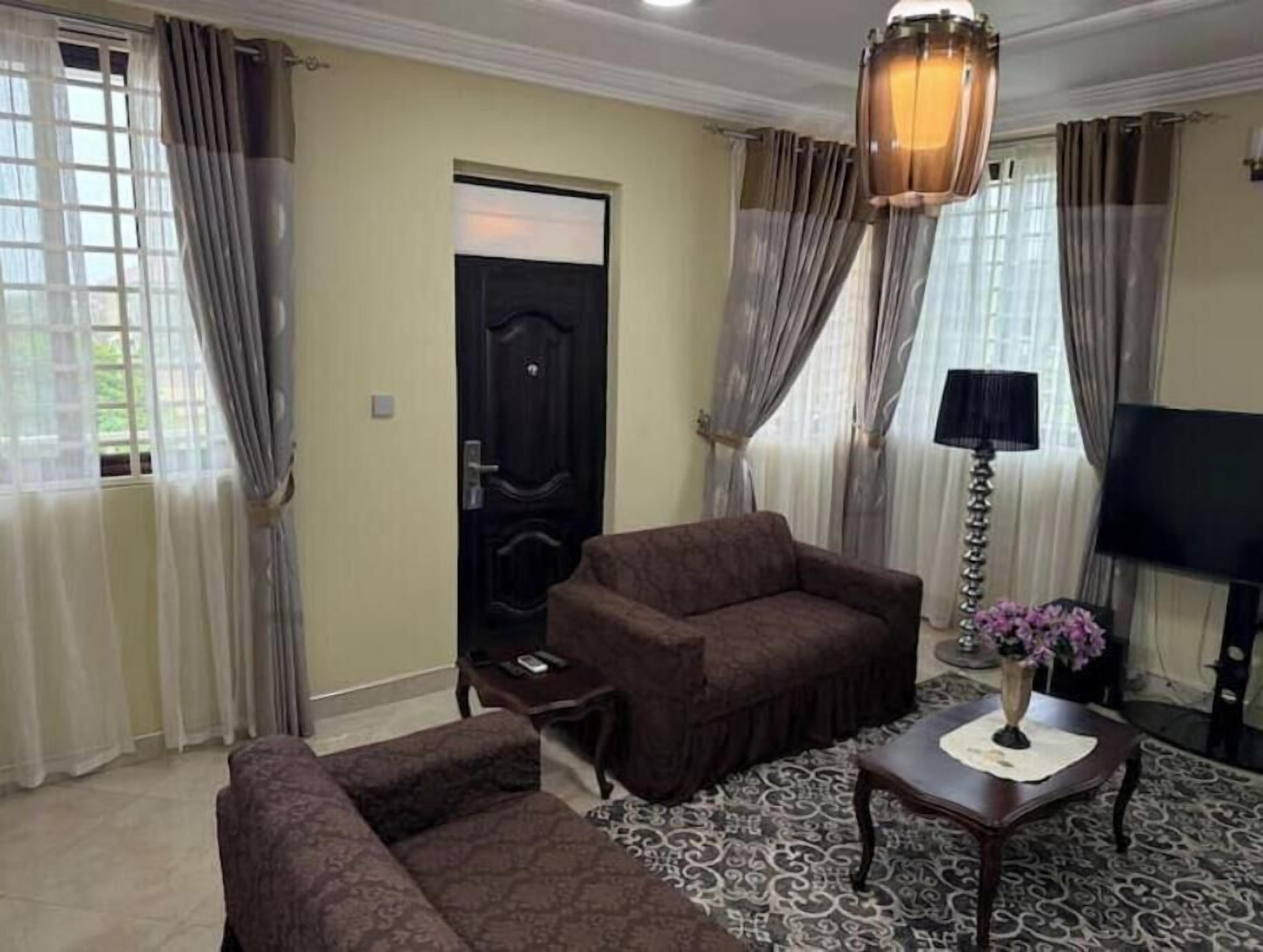 A living room with a sofa, armchair, and a small table with a vase.