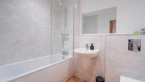 Un bagno moderno con cabina doccia in vetro, un lavandino bianco e uno specchio.