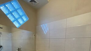 Un baño moderno con tragaluz, lavabo, inodoro y espejo.