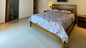 Un dormitorio con cama, mesita de noche, aire acondicionado de pared y una puerta que da al baño.