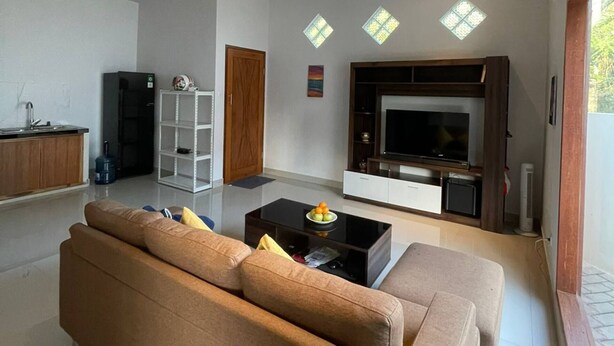 Una sala de estar moderna con un sofá, una mesa de centro, un televisor y una cocina al fondo.