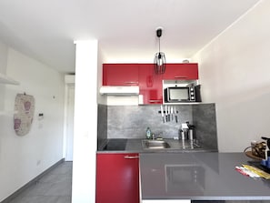A compact kitchen with a microwave, sink, and red cabinets. - Balcon Jean Jaures 3 City Center (Nice)