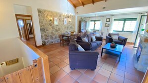 A spacious living area with a stone wall, a dining table, and comfortable seating. - El Secreto de las Eras - Charming rural house in Candelario, nature (Candelario)