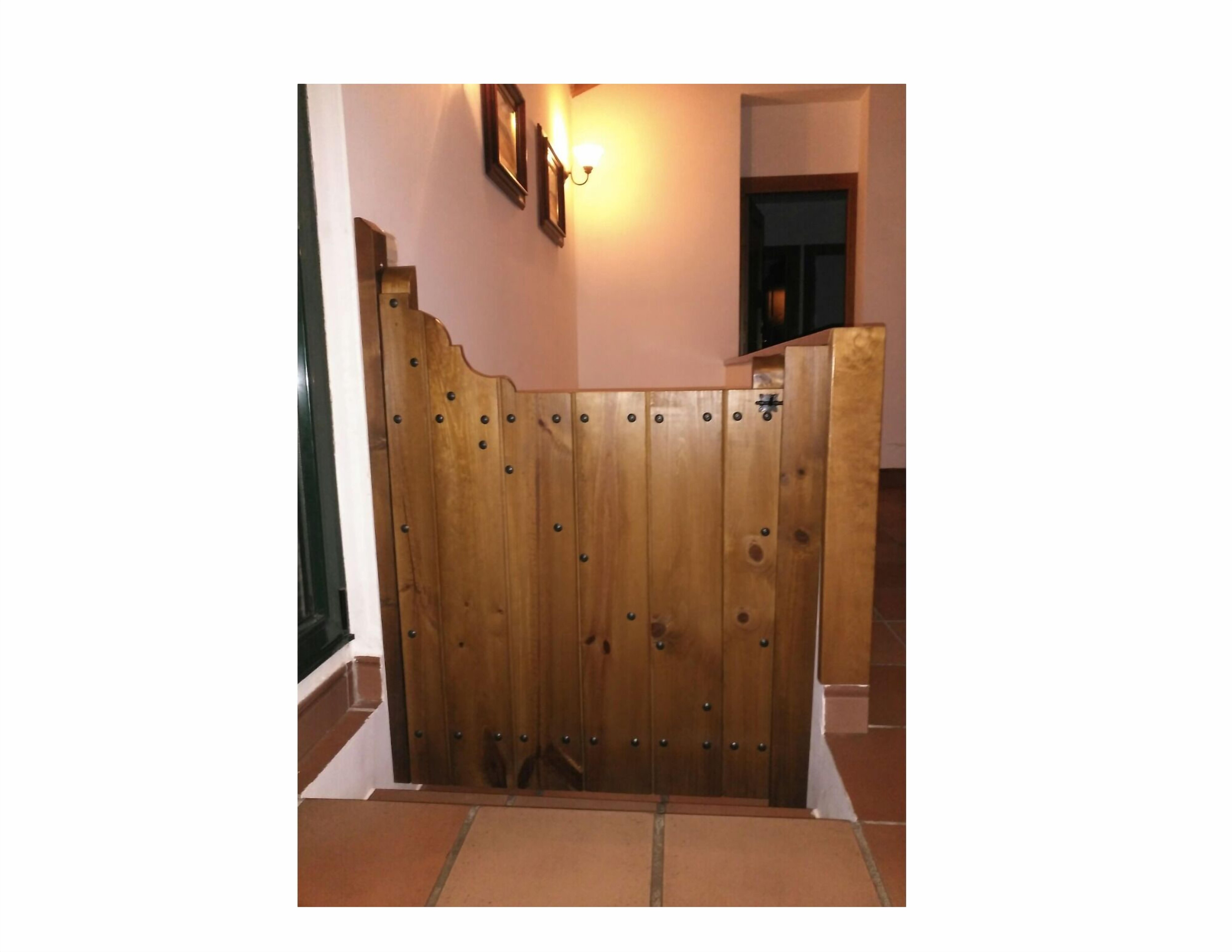 Una verja de madera con remaches metálicos, un accesorio de luz fijado a la pared y un marco de puerta.