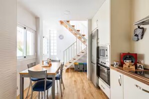 A compact kitchen with a wooden staircase, a dining area with chairs, and a refrigerator. - Spacious and bright apartment with large private roof terrace-solarium. (Nerja)