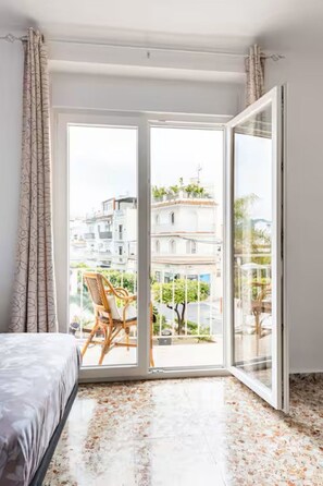 A bedroom with a bed, a chair, a large sliding glass door, and a view of buildings outside. - Spacious and bright apartment with large private roof terrace-solarium. (Nerja)