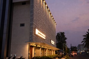 Un edificio moderno con fachada texturizada, señalización iluminada y una zona de acceso cubierta.