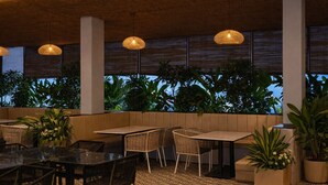 An outdoor seating area with tables and chairs, surrounded by potted plants and a view of the sky.
