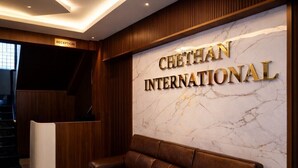 A reception area with a marble wall, a reception desk, and a leather sofa.