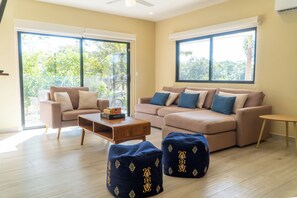 A modern living room with a beige sofa, a wooden coffee table, and two blue poufs. - Luxury 6BR Villa - Private Pool - Walk to Beach - Tamarindo (Tamarindo)