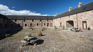 A courtyard with stone buildings, a stone floor, and outdoor seating. - Ayrshire Cottage at The Dairy at Daviot (Inverness)