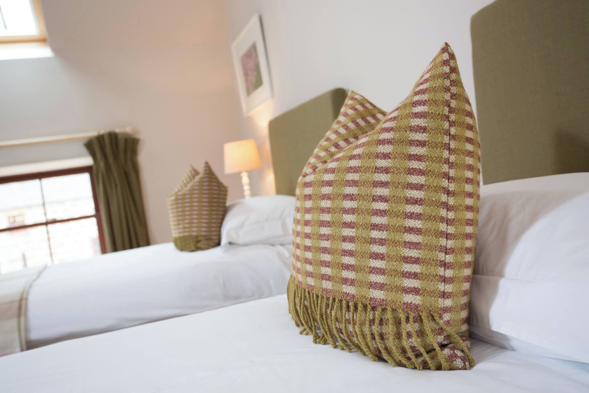 Habitación de hotel con cama, almohadas, lámpara y ventana con cortinas.