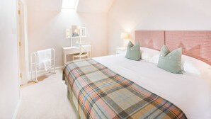 A bedroom with a bed, a desk, a chair, a window, and a headboard. - Ayrshire Cottage at The Dairy at Daviot (Inverness)