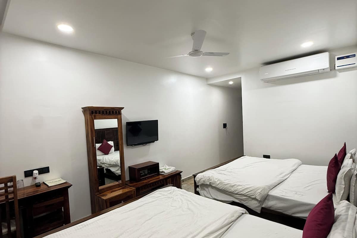 A hotel room with two beds, a TV, a ceiling fan, and an air conditioning unit.