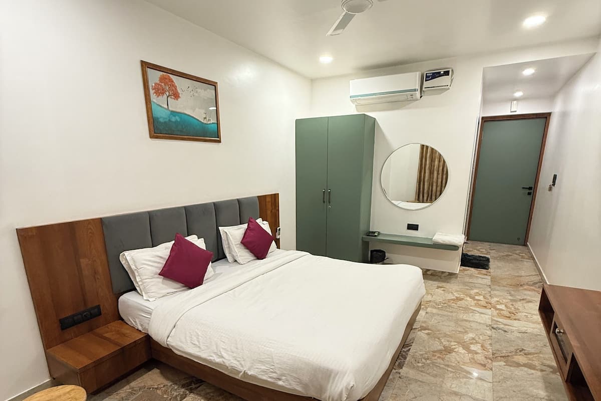 A bedroom with a bed, a ceiling fan, a wardrobe, a mirror, and a bathroom door.