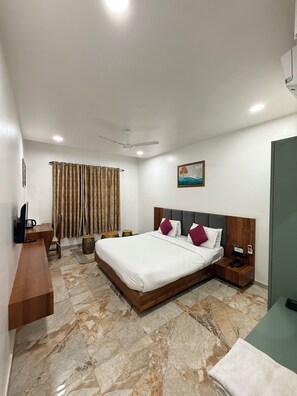 Une chambre d’hôtel moderne équipée d’un grand lit, d’un bureau, d’une chaise, d’une télévision, d’un tableau et d’un téléphone.