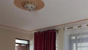 Une pièce avec une porte en bois, un rideau rouge, un rideau blanc et un sol carrelé.