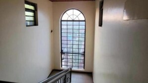Un escalier avec un plafond en bois, une petite fenêtre et une rampe en métal.