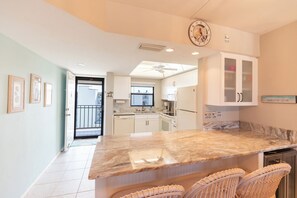 A kitchen with a marble countertop, white cabinets, and a ceiling fan. - Fun In Sun On A Budget! 2B/2B Condo w/ Pool & Tennis! Walk to Beach! EC163 (Fort Myers Beach)