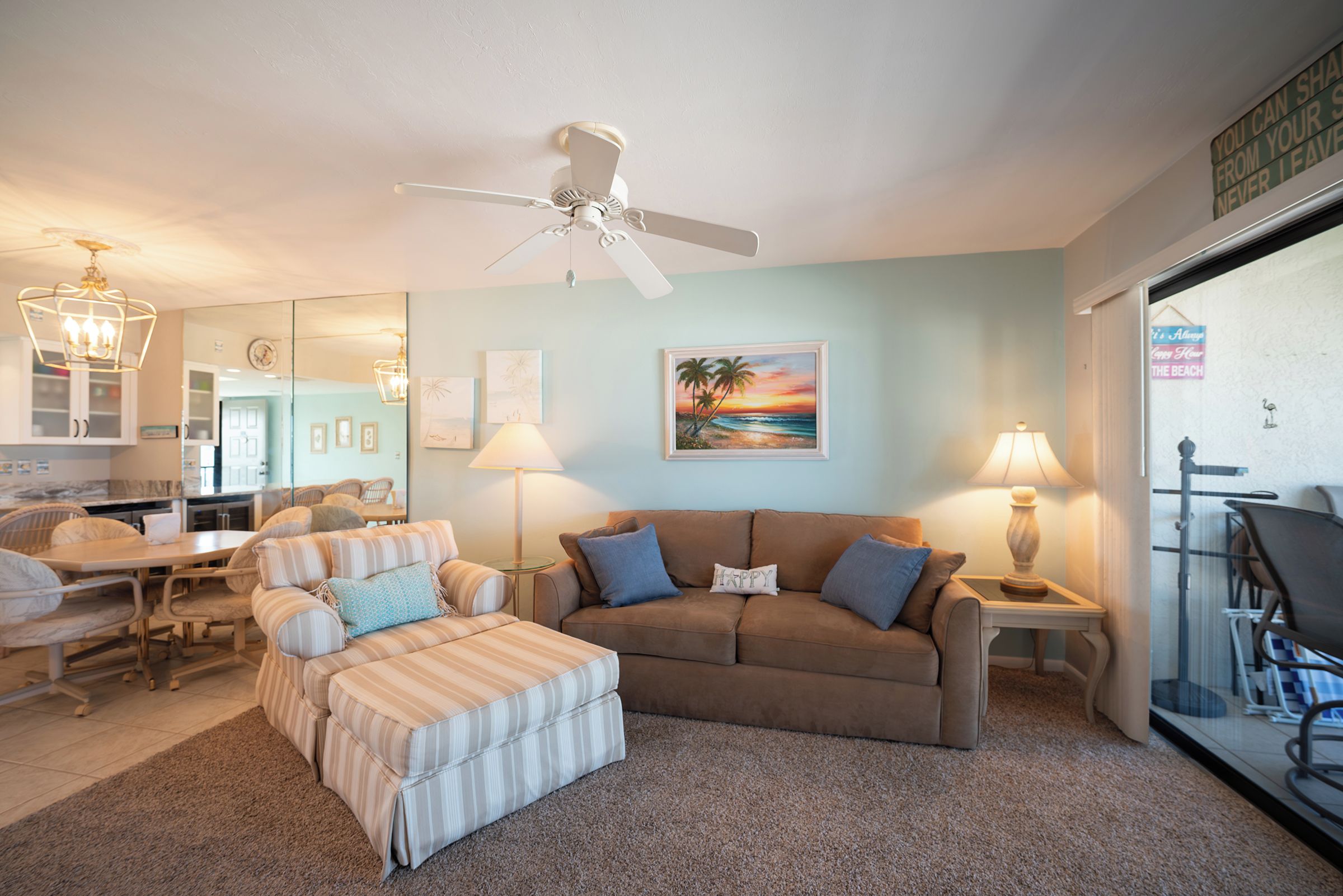 A living room with a sofa, ottoman, and a ceiling fan.