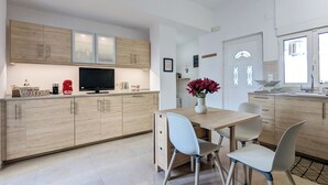 Una cocina moderna con armarios de madera, una mesa de comedor con sillas, un televisor y un florero con flores.