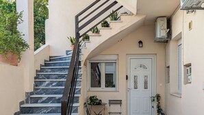 Una escalera que lleva a una puerta, con una pequeña mesa y sillas afuera.