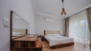 Ein Hotelzimmer mit einem hölzernen Bett, einem Schreibtisch aus Holz, einem großen Spiegel und einer Pendelleuchte.