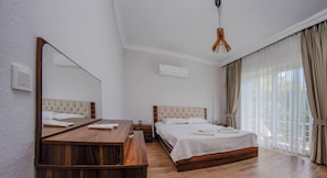 A hotel room with a wooden bed, a wooden desk, a large mirror, and a hanging light fixture. - Fethiye Göcek Villa Begonvilla (Fethiye)