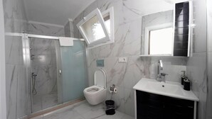 Ein Badezimmer mit Glasdusche, Toilette, Waschbecken und Spiegel.