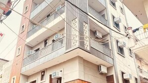 A multi-story building with balconies, air conditioning units, and a ground-level commercial space with a closed shutter. - Staylo The Royal  (New Delhi)