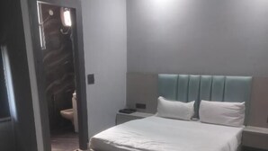 A modern hotel room with a large bed, bedside tables, a desk, and a chair. - Staylo The Royal  (New Delhi)