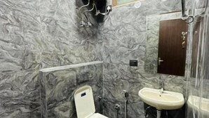A bathroom with a toilet, bidet, sink, and shower. - Staylo The Royal  (New Delhi)
