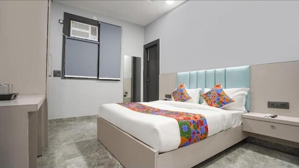 A modern bedroom with a bed, bedside tables, a wardrobe, and an air conditioning unit. - Staylo The Royal  (New Delhi)