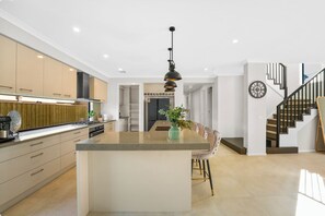Une cuisine moderne dotée d’un îlot central, d’un coin repas avec une chaise et d’un escalier menant à l’étage supérieur.