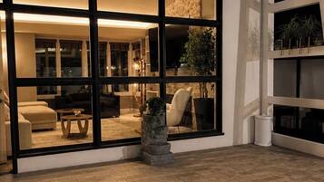 A modern interior with a large glass door leading to a living area with a sofa, coffee table, and a potted plant.