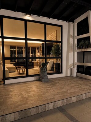 A modern interior with a large glass door leading to a living area with a sofa, coffee table, and a potted plant.