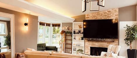 Una sala de estar moderna con un sofá grande, una mesa de comedor con sillas, un televisor y una chimenea.