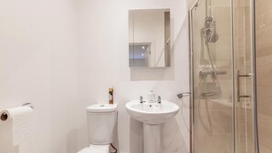 Une salle de bain équipée de toilettes, d’un lavabo et d’une douche à parois de verre.