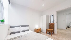 Una camera da letto con un letto, un comodino, una sedia, un armadio e uno specchio.