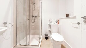 Un bagno moderno con doccia vetro, water bianco e lavandino.